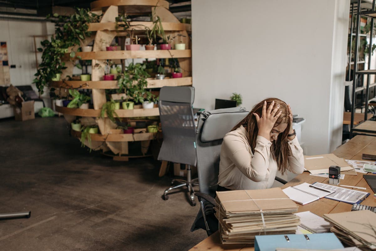 Person overwhelmed by stacks of paperwork at their desk