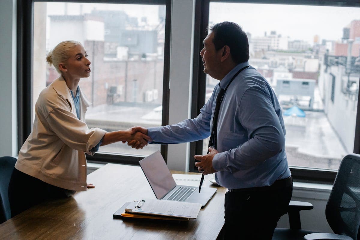 Employer and employee shaking hands after signing a contract in an office
