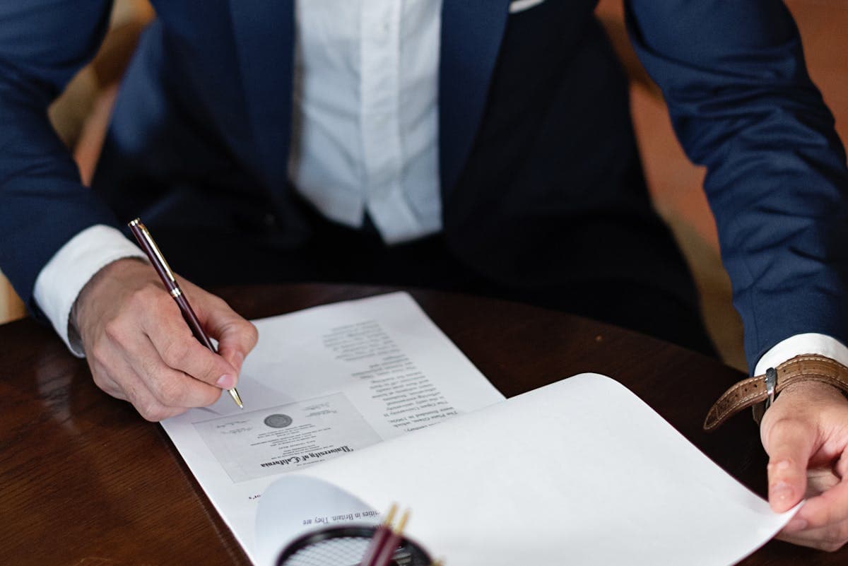 Professional signing employment documents at a desk